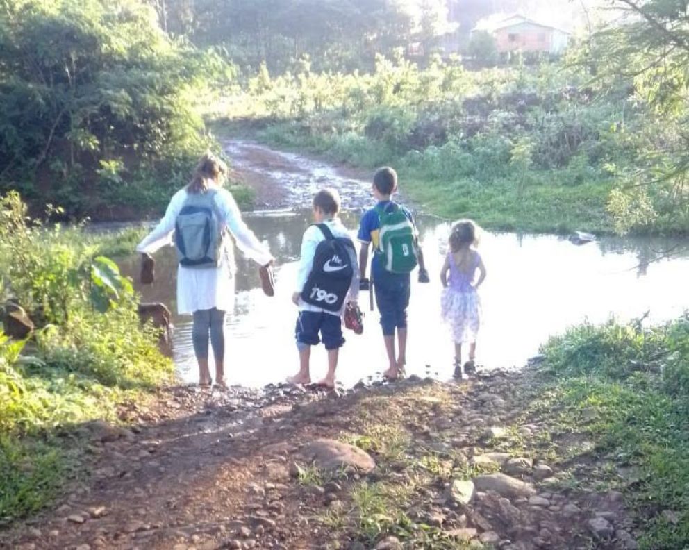 Niños cruzan por un arroyo para llegar a la escuela por falta de puente