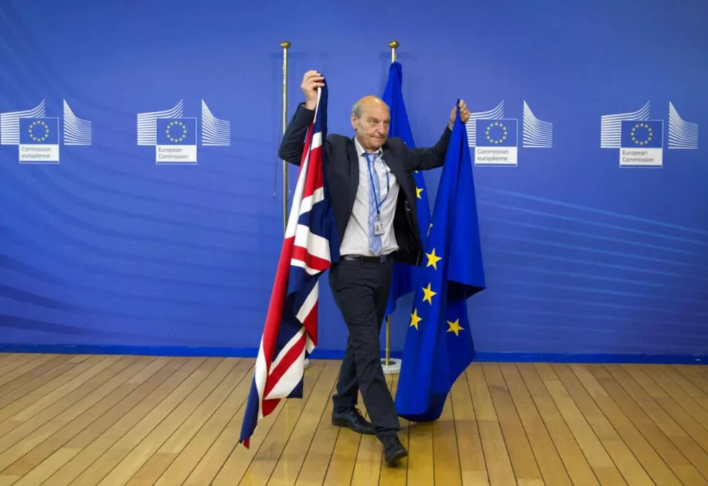 Foto tomada en junio de 2017, tras una conferencia de prensa un empleado de protocolo se lleva las banderas británicas y de la UE