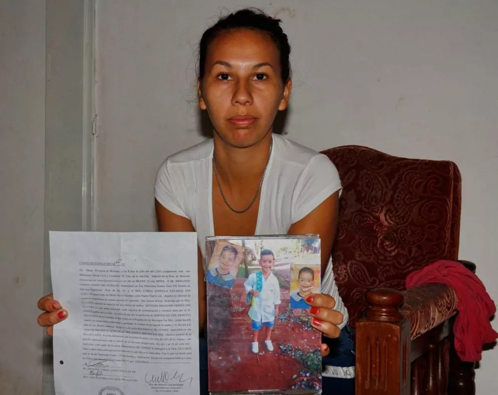 Carla, junto a un documento y la imagen de su hijo de 7 años.