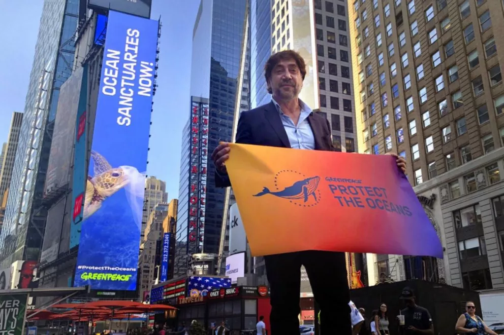 Javier Bardem posando en Times Square con la bandera de Greenpeace para salvar los oceanos