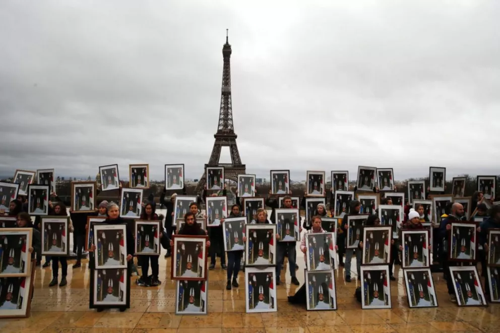 Los activistas se fotografiaron en París con los retratos robados de Macron puestos boca abajo