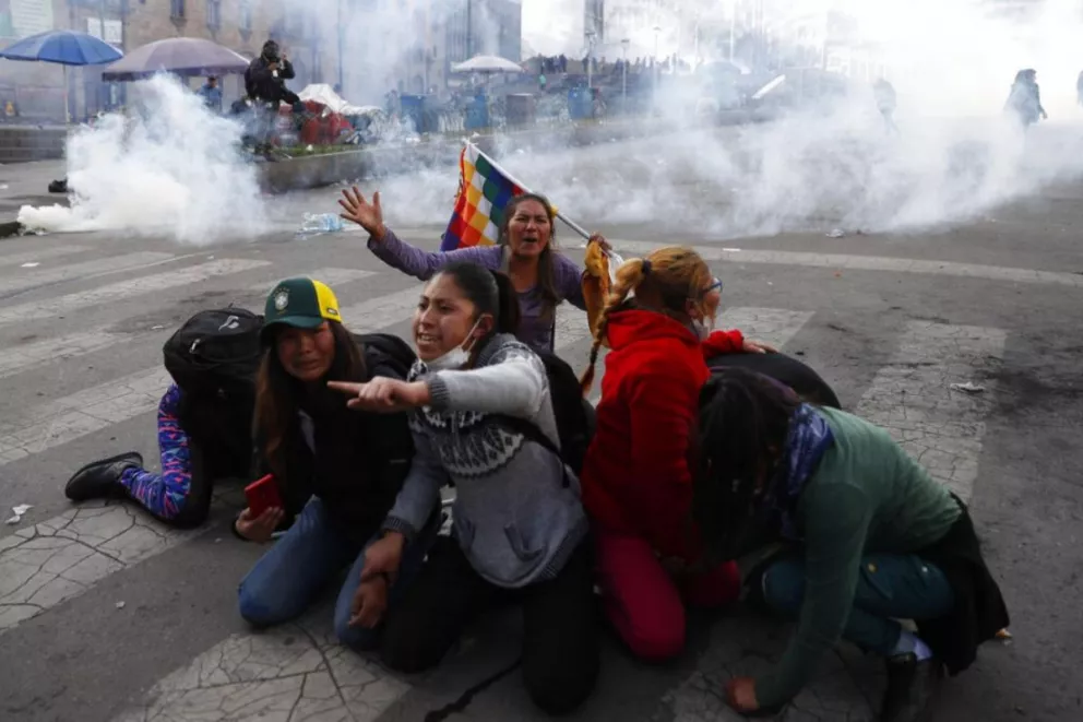 En esta foto de archivo del 15 de noviembre de 2019 partidarios del expresidente Evo Morales se protegen del gas lacrimógeno lanzado por la policía en La Paz, Bolivia
