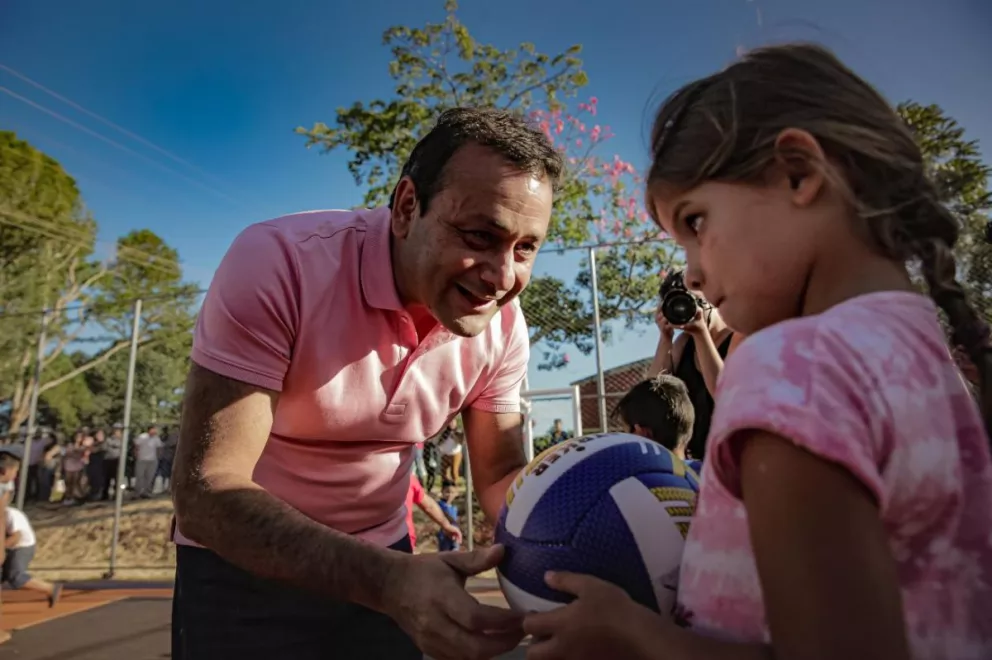 Oscar Herrera Ahuad le entrega una pelota a una niña durante la inauguración del playón en Campo Grande