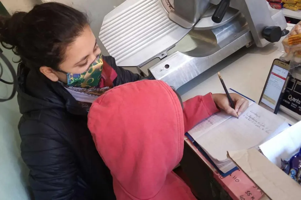 Luana, entre la tarea del niño y su trabajo en el almacén.
