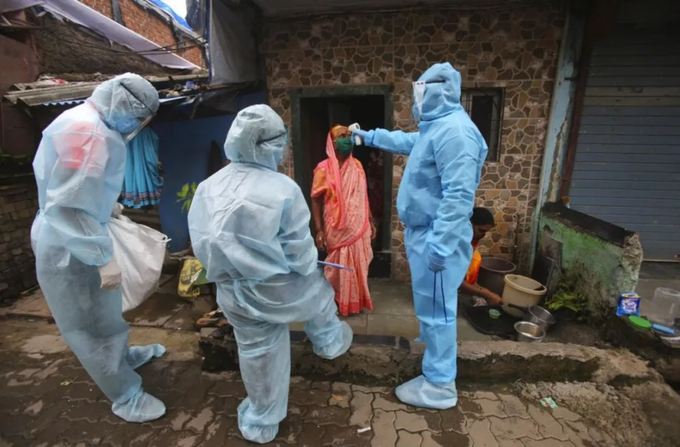 Trabajadores de la salud controlan la temperatura en uno de los barrios de la India donde aparecieron rebrotes de Covid-19
